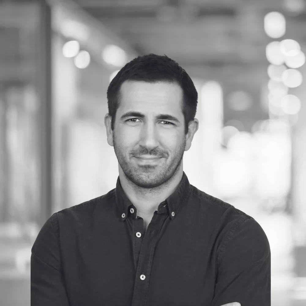A grayscale photo of Jacob Karaduman. A startup advisor for growup. he is smiling and wearing a black shirt.
