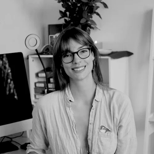 A greyscale image of Helga Timarovsky. She is smiling with round glasses and a white button up shirt. She is a copywriter for growup. 